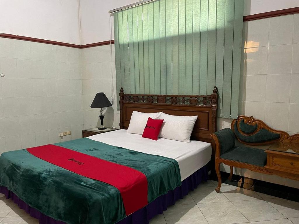 a bedroom with a large bed and a chair at RedDoorz Syariah @ Karang Pilang in Karangpilang