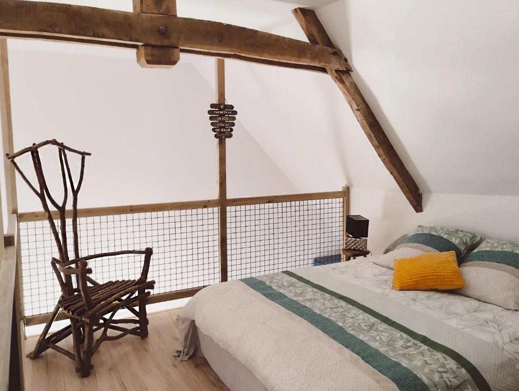 1 dormitorio con cama y silla de madera en LOFT Le chant des Oiseaux proche Mont St Michel, en Pleine-Fougères