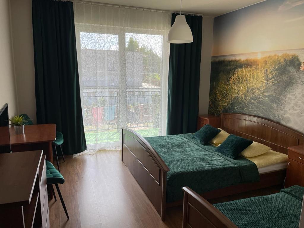 a bedroom with two beds and a window at Emada- Pokoje Gościnne i Studia in Ostrowo