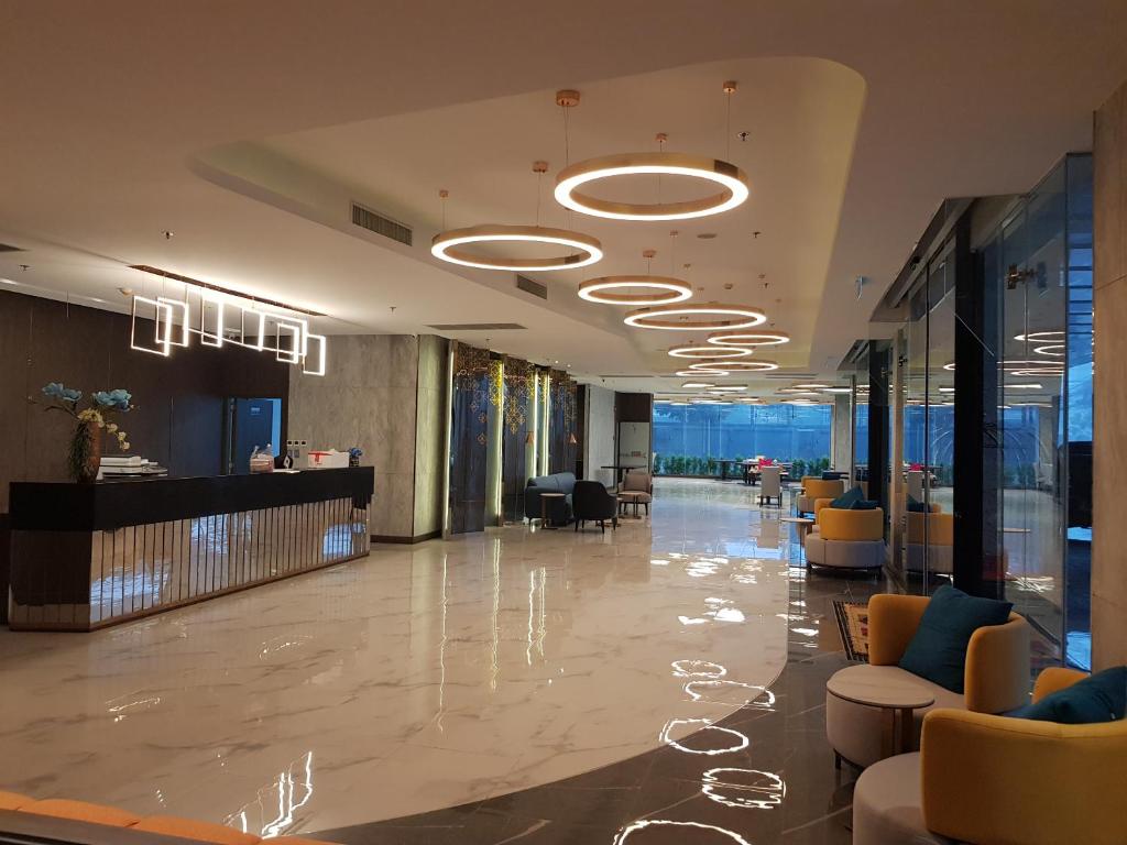 A spacious modern lobby leads from the reception desk toward a bright windowed area.