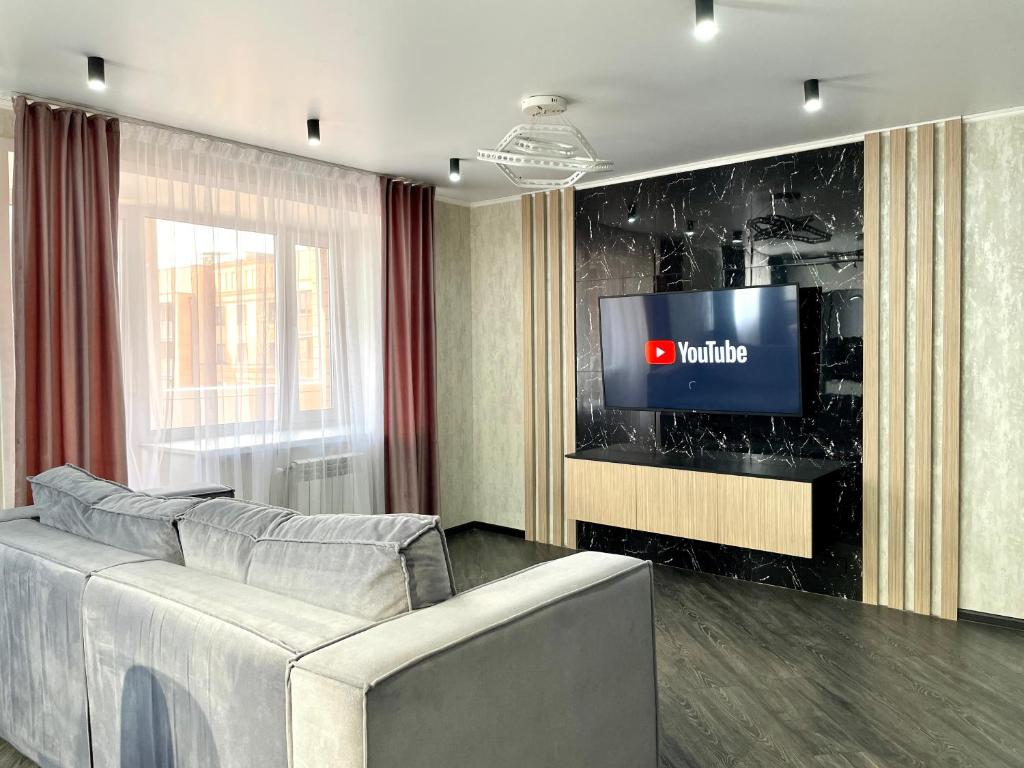 sala de estar con sofá y TV en Новостройка с дизайнерским ремонтом, en Petropavlovsk