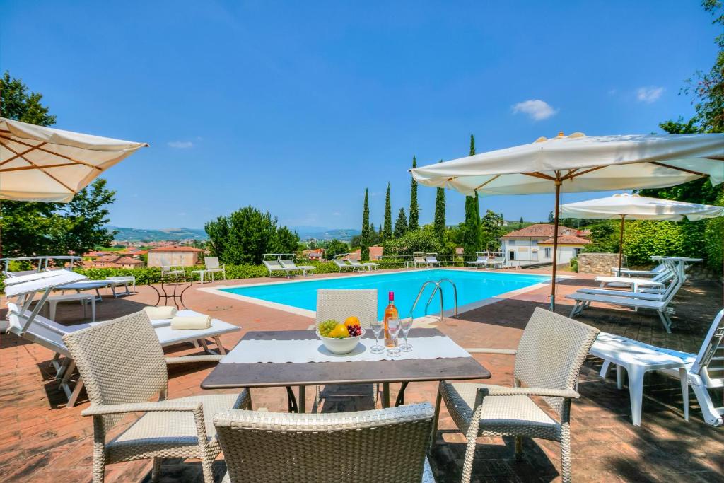 un patio con mesa, sillas y piscina en Villa Faccioli Magnolia And Oleandro With Shared Pool - Happy Rentals, en Colognola ai Colli