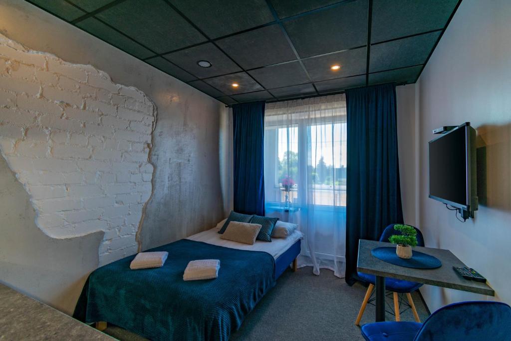 Cette chambre comprend un lit, une table et une télévision. dans l'établissement Apartments24 Ilu, à Rakvere