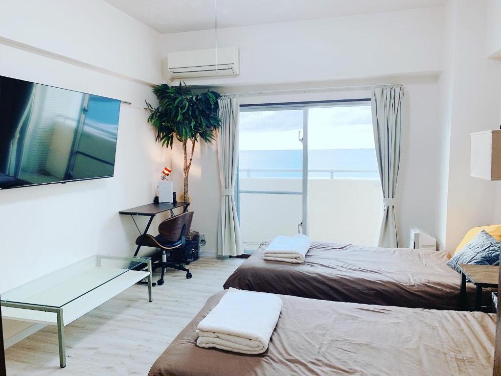 Pokój z 2 łóżkami, biurkiem i oknem w obiekcie ウィンベル沖縄名護コーラルビュー w mieście Agarii