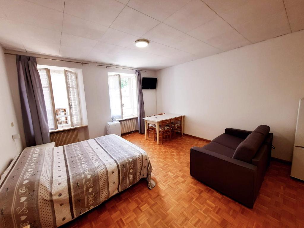 a bedroom with a bed and a couch and windows at Adler Apart in Trento