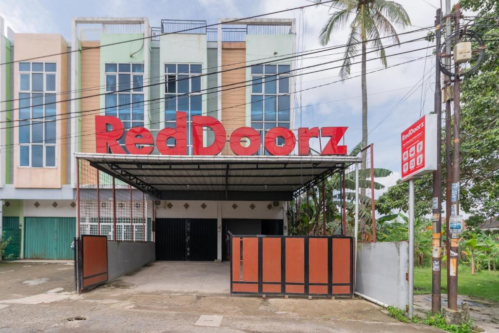una señal de puerta roja en la parte delantera de un edificio en RedDoorz near Palembang Trade Center 4 en Sukarami