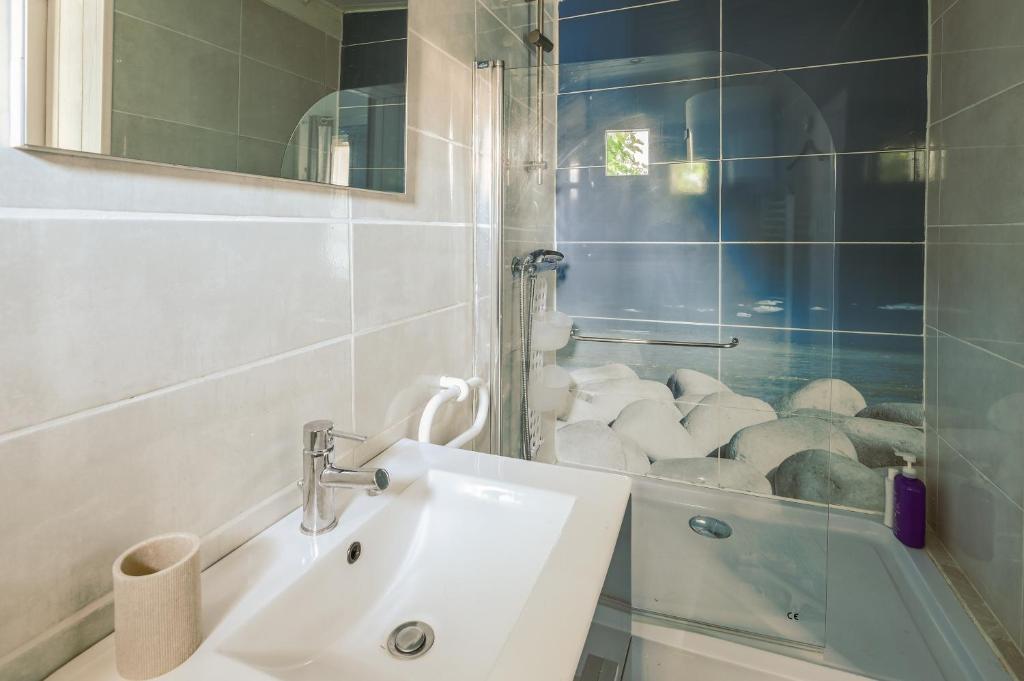 łazienka z umywalką i przeszkloną kabiną prysznicową w obiekcie Maison agréable et tranquille w mieście Gujan-Mestras