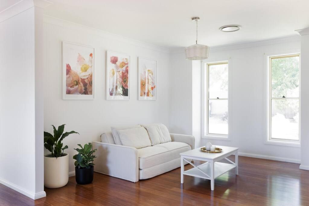 a white living room with a couch and a table at Adorable 1-bedroom Kuzman Guesthouse in Mudgee