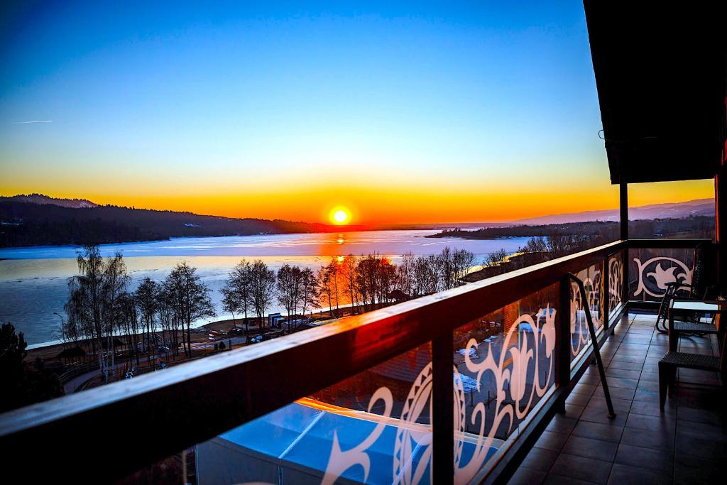 a sunset from a balcony with a view of a lake at Apartament 33 Lake & View Centralny Widok na Jezioro -100 metrów od Jeziora Czorsztyńskiego i ścieżki rowerowej Velo Czorsztyn in Kluszkowce