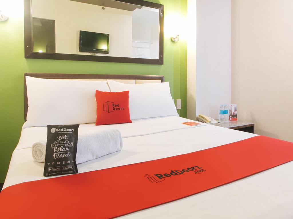un letto con cuscino rosso e specchio di RedDoorz @ Express Inn Lapu Lapu a Pajo