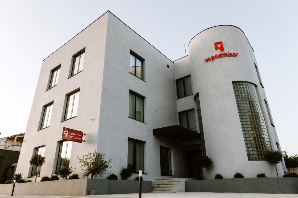 - un bâtiment blanc avec un panneau rouge dans l'établissement Hotel Septembar, à Podgorica