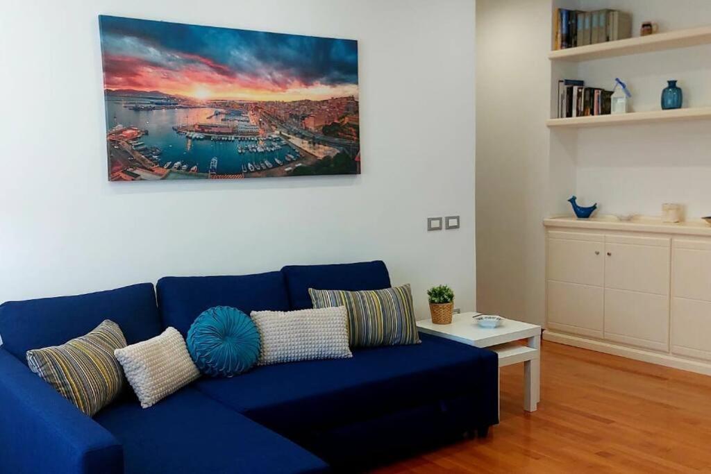 um sofá azul numa sala de estar com um quadro na parede em Blue Apartment em Cagliari