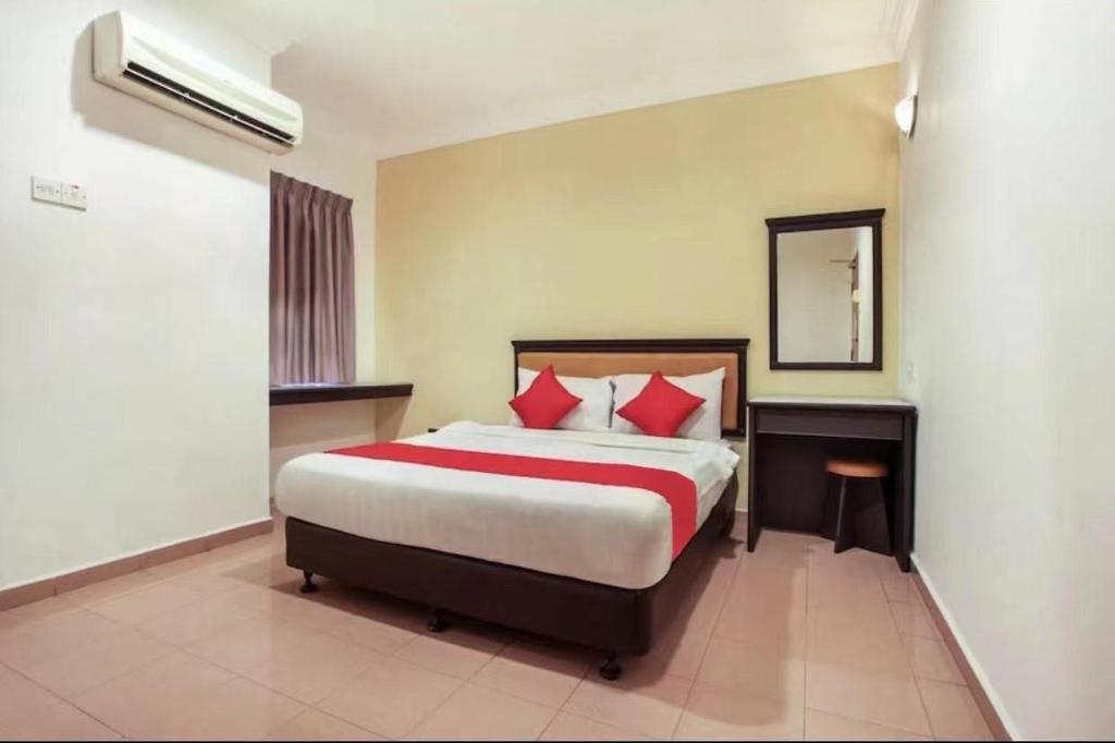 Schlafzimmer mit einem Bett mit roten Kissen und einem Spiegel in der Unterkunft Hotel Home 88 in Teluk Intan