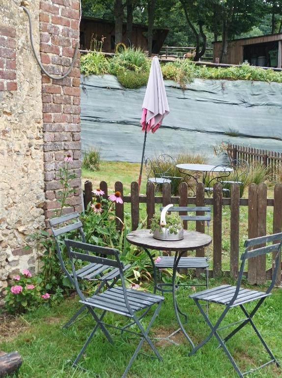 einen Tisch und Stühle mit Sonnenschirm im Hof in der Unterkunft Maisonnette en campagne "Le Rocher" in Vibraye