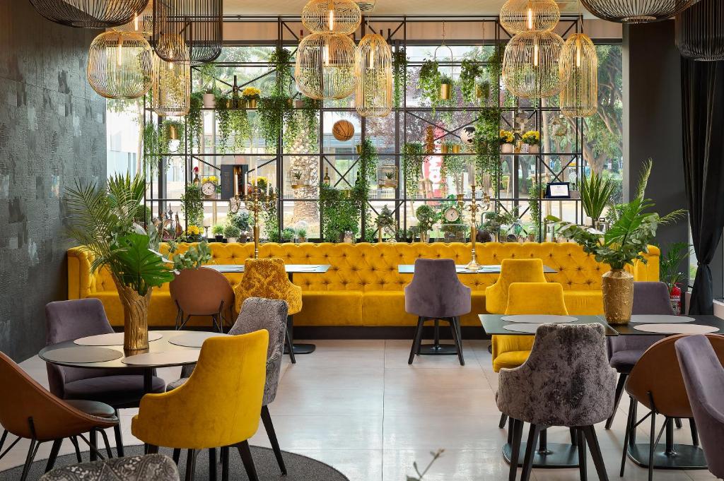 a restaurant with yellow chairs and tables and plants at Sia Split Hotel in Split