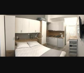 a bedroom with a white bed and a kitchen at Studio Antonio New in Zadar