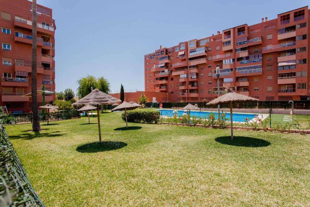 un parque con sombrillas, una piscina y un edificio en Apartamento Teatinos, en Málaga