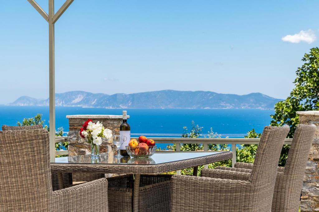 einen Tisch mit Blumen, eine Flasche Wein und Stühle in der Unterkunft Vainas Belvedere Villa in Skopelos