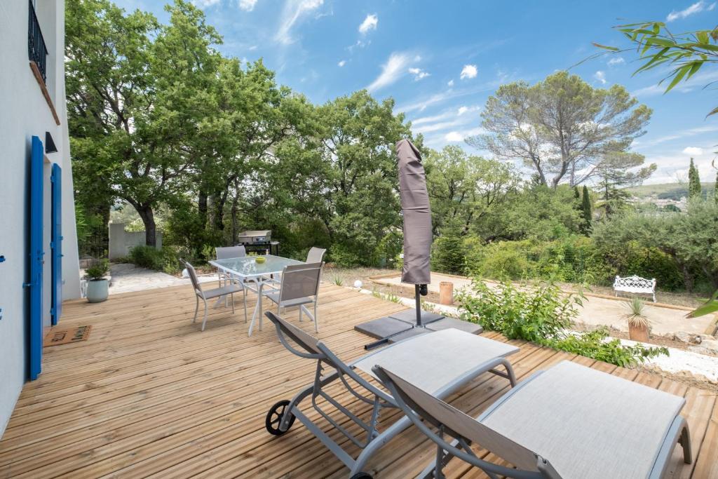 a wooden deck with chairs and a table with an umbrella at REVES DE PAMPA l APPART in Lorgues