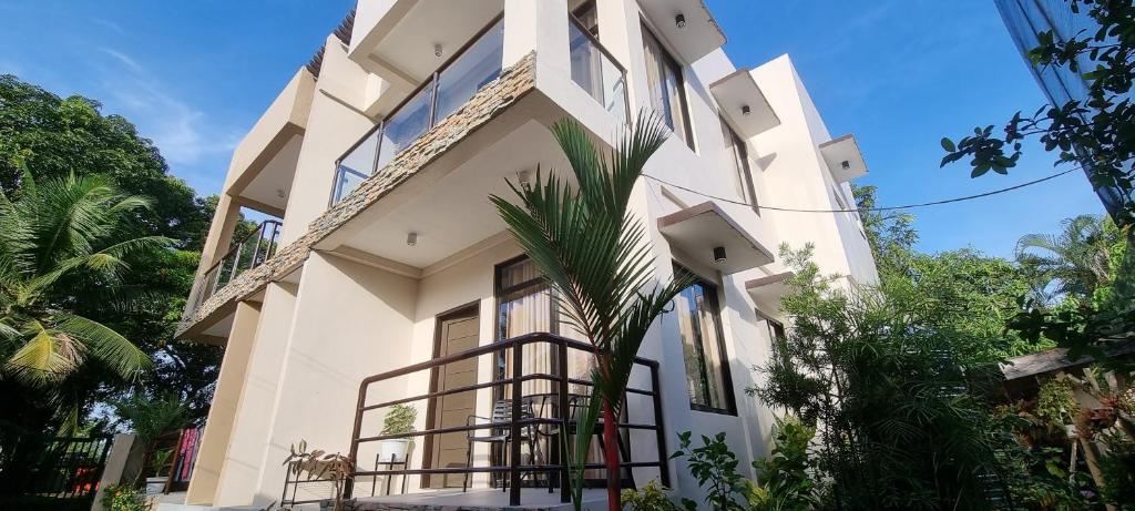 a white building with a palm tree in front of it at Tagoloan 'Boutique' Apartments in Aplaya