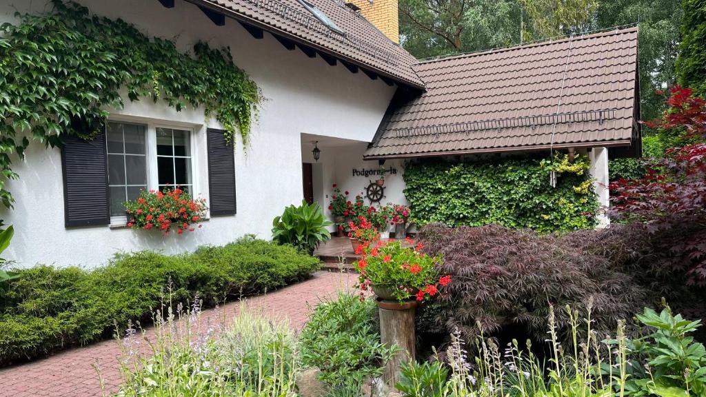 a white house with black shutters and a garden at Lapalice Holiday Home in Łapalice