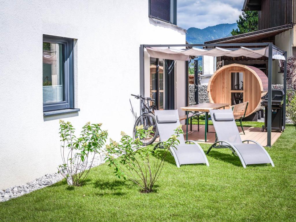 - un jardin avec une table, des chaises et un parasol dans l'établissement Apartments Frauensee, à Reutte