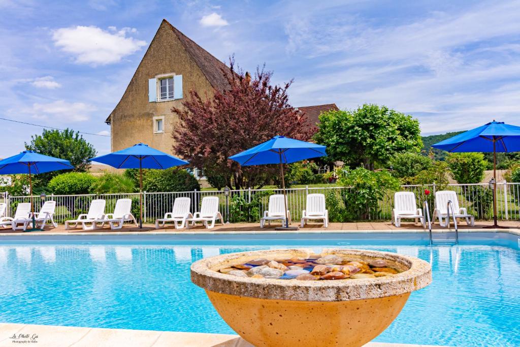 a swimming pool with chairs and blue umbrellas at Le Relais des 5 Chateaux in Vézac