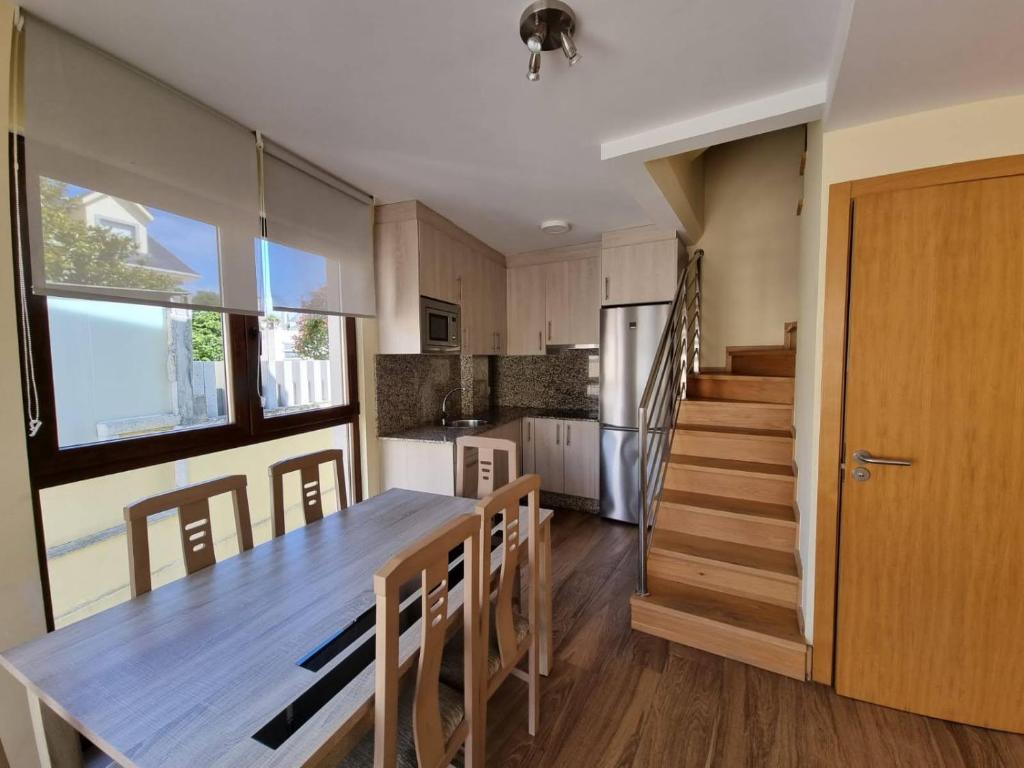 een keuken en eetkamer met een tafel en een trap bij Foz Playa Rapadoira - 2 dormitorios in Foz