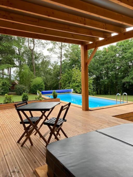 un patio avec une table et des chaises et une piscine dans l'établissement Lodge La Courrège, à Larché