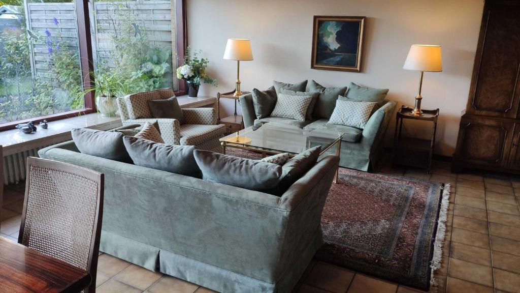 ein Wohnzimmer mit einem großen Sofa und Stühlen in der Unterkunft Ferienhaus an der Förde in Flensburg