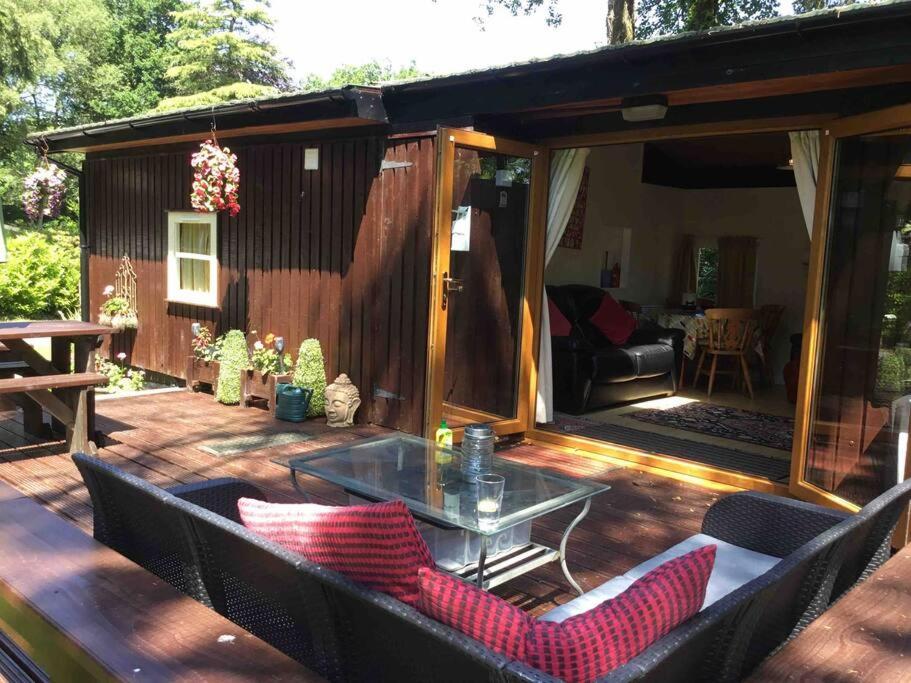 un patio con una mesa de cristal en una terraza de madera en lovely log cabin on woodland site en Cenarth