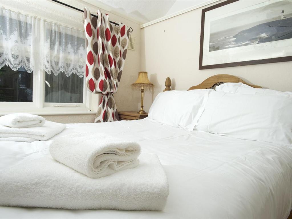 um quarto com uma cama branca e toalhas em The Endeavour em Whitby