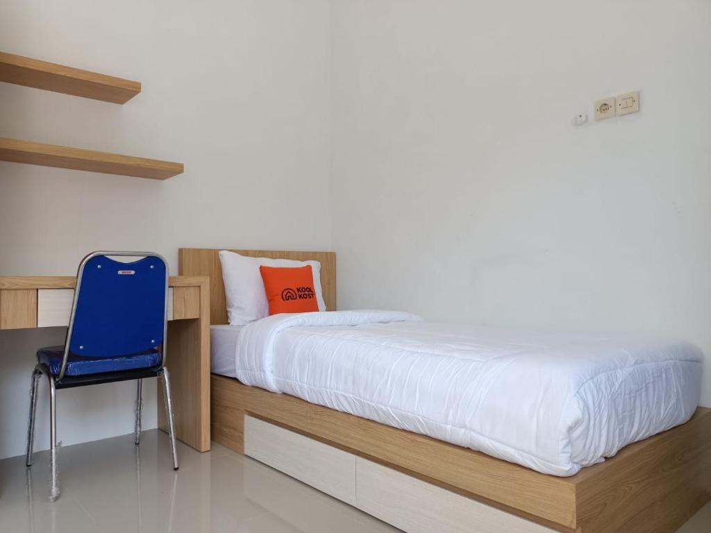 1 dormitorio con 1 cama y 1 silla azul en KoolKost Female Syariah near Universitas Ahmad Dahlan Kampus 3 - Minimum Stay 30 Nights, en Timuran