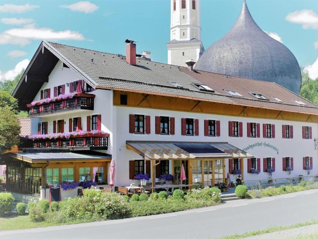 ein großes weißes Gebäude mit einem Uhrturm in der Unterkunft Gasthof Huberwirt GmbH in Rosenheim