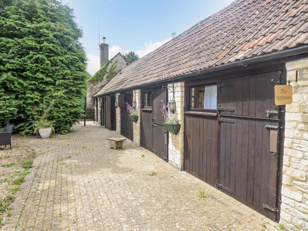 uma fileira de edifícios com portas e um passeio de tijolos em The Old Stables em Chippenham