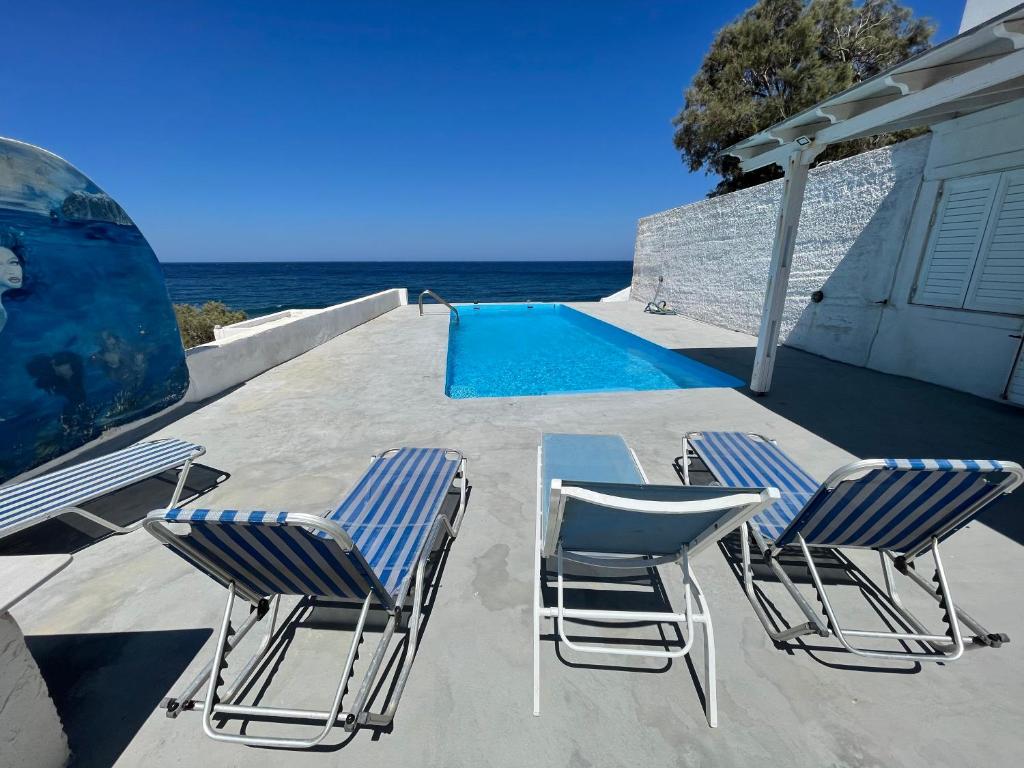 2 sillas y una mesa junto a la piscina en Santorini Grace Villa 3 en Foinikiá