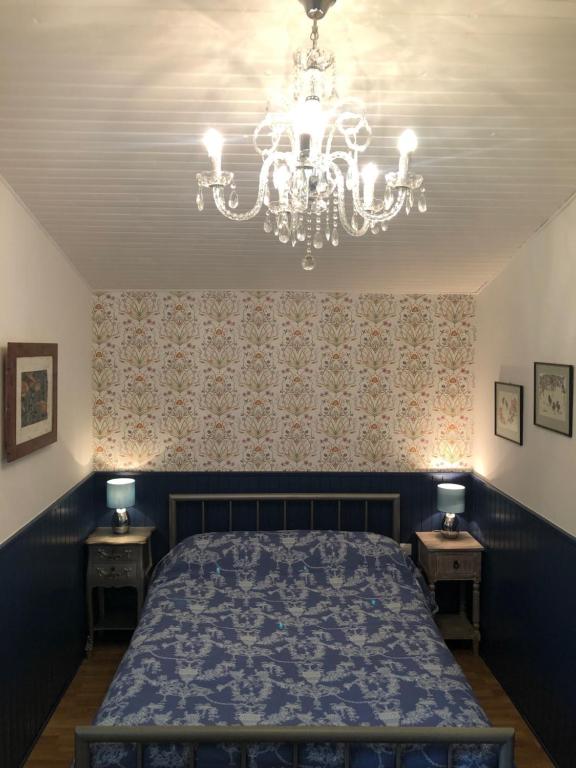 een slaapkamer met een bed en een kroonluchter bij Holli cottage - Charming 2 bedrooms with terrace. in Saint-Avit-Rivière