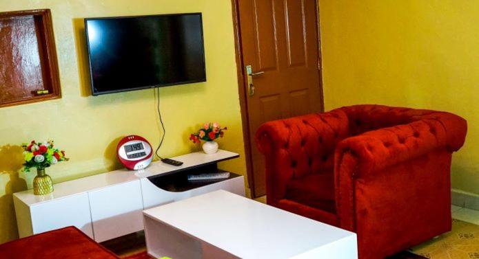 a living room with a red chair and a television at Claire's apartments 1,2 and 3 ensuite bedrooms in Kisumu