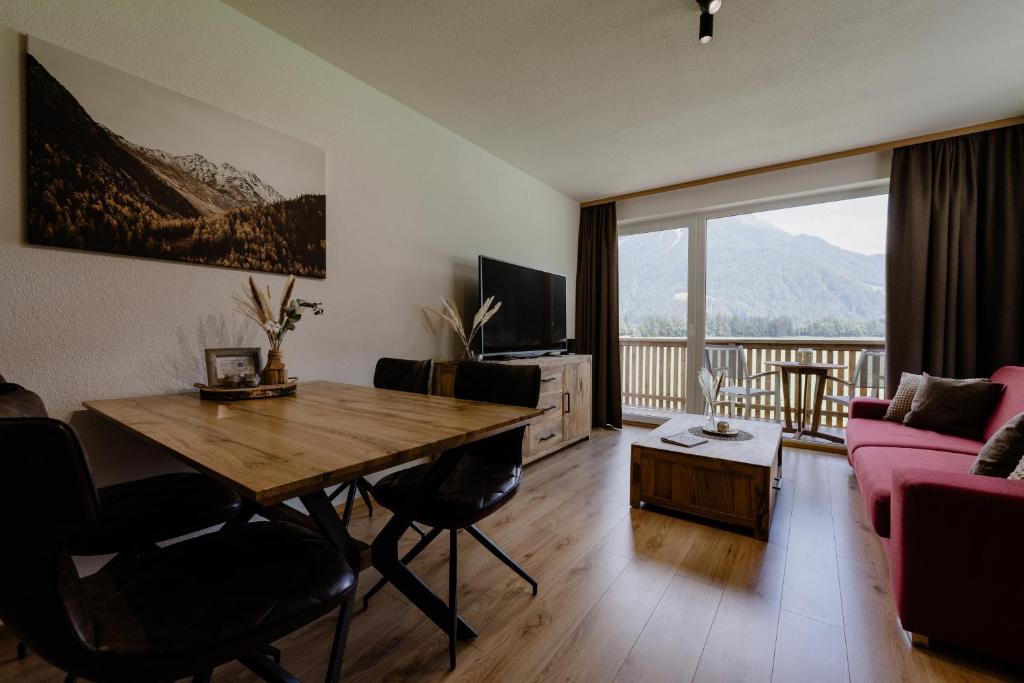 a living room with a wooden table and a balcony at Apart Peak Ötztal in Längenfeld