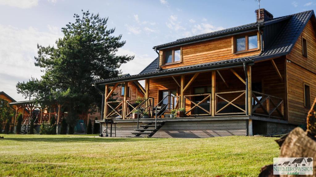 ein großes Holzhaus mit einer großen Veranda in der Unterkunft Niemirowska Osada in Niemirów