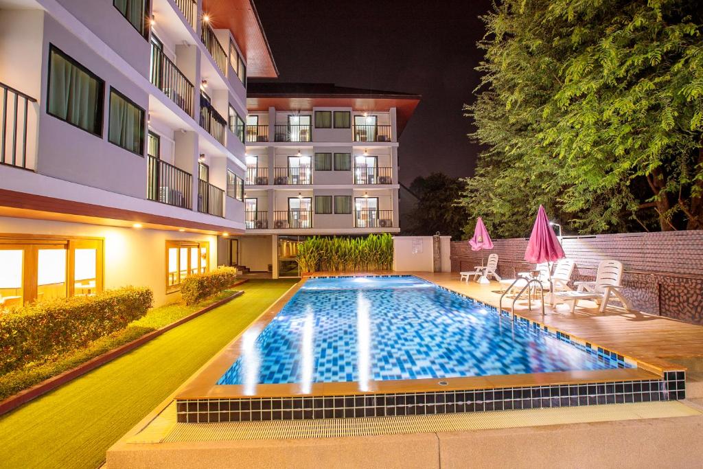 a swimming pool in front of a building at night at Huen Jao Ban Hotel in Chiang Mai