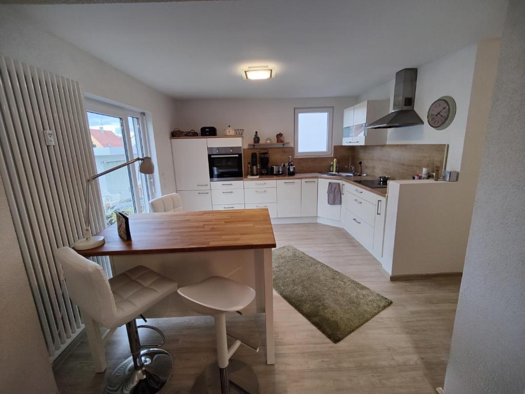 cocina con armarios blancos y mesa de madera en Apartment Lia, en Beerfelden