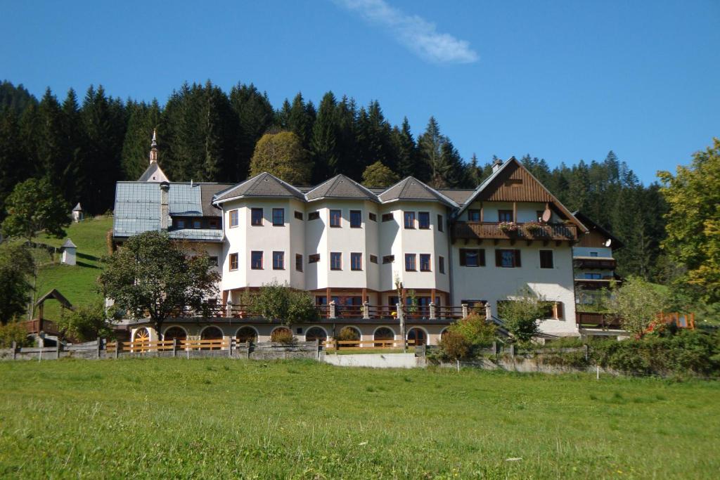 een groot huis op een heuvel in een veld bij Haus der Begegnung in Gosau