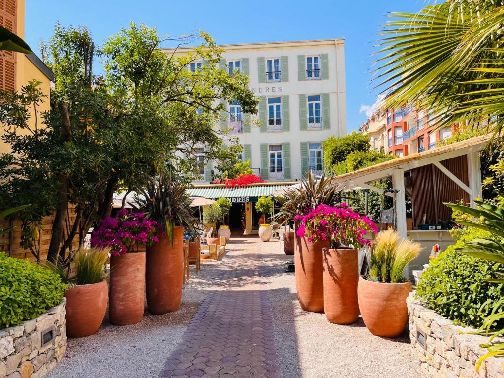 una calle con muchas macetas y un edificio en Hôtel De Londres, en Menton