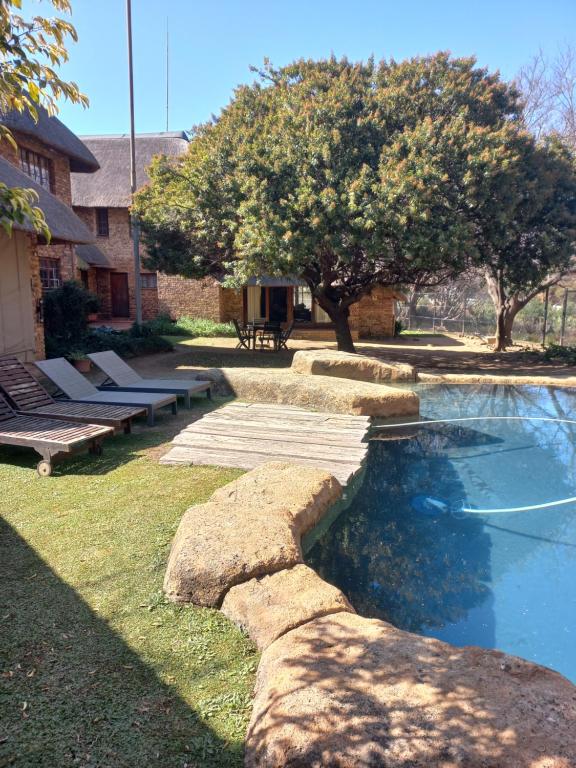 een zwembad in een tuin met bomen en banken bij Khaya Africa Guesthouse in Midrand
