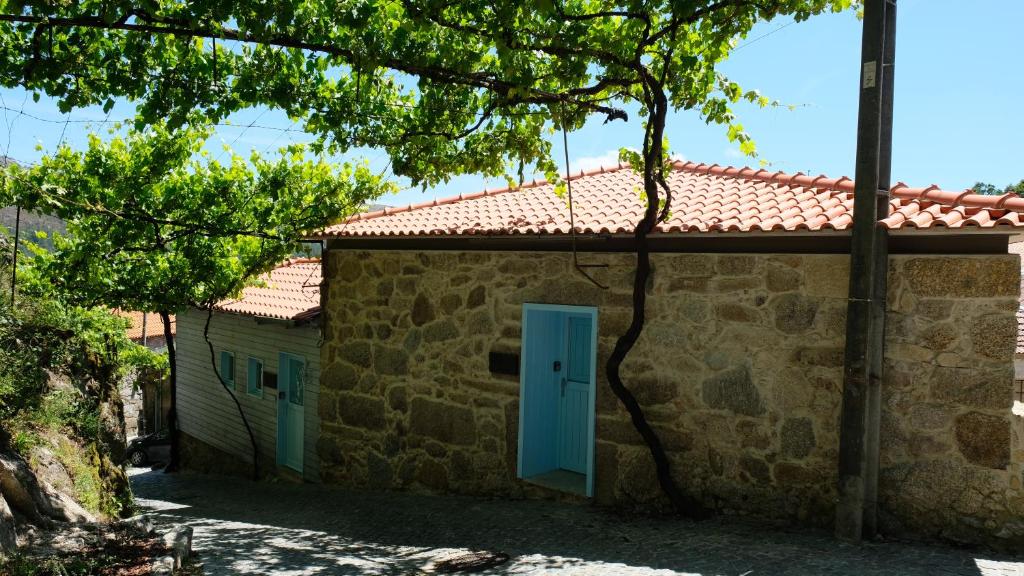 un edificio con una puerta azul y un árbol en Casa Tritão, en Campo do Gerês
