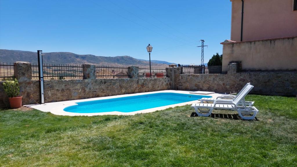 a swimming pool with a chair in a yard at La casa de Pi in Torrecaballeros