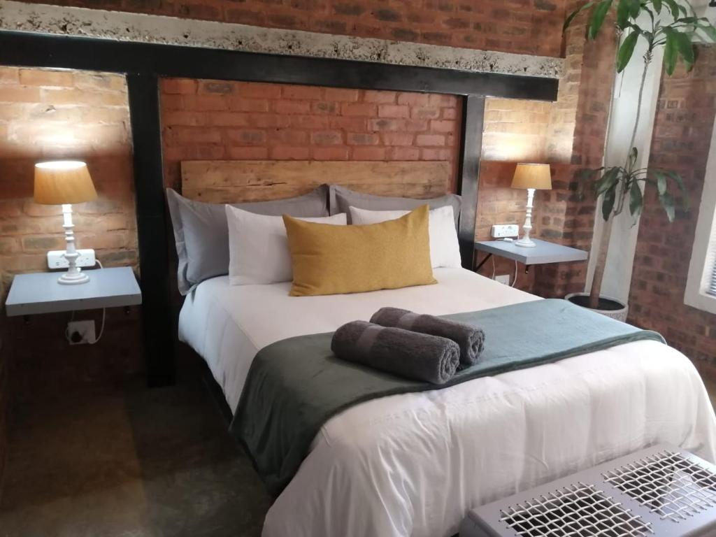 ein Schlafzimmer mit einem großen weißen Bett mit zwei Tischen in der Unterkunft Wild Olive Cottage in Hartbeespoort in Pretoria