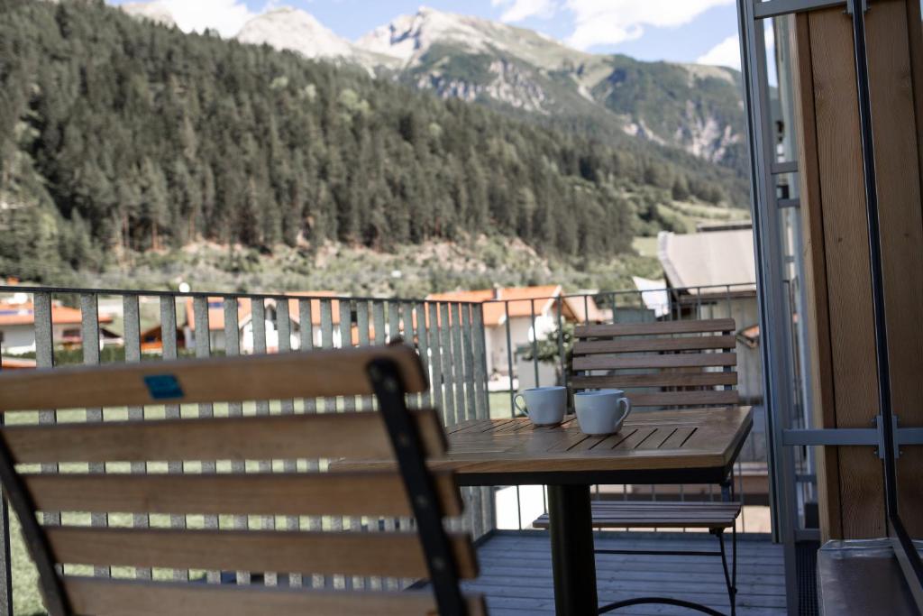 a table and chairs on a balcony with a view of a mountain at Arlberg Mountain Resort in Pettneu am Arlberg