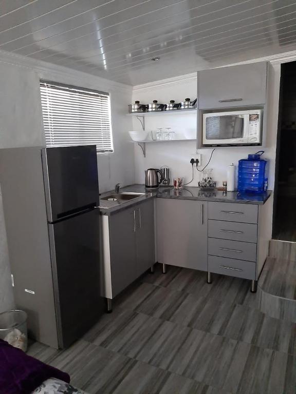 uma pequena cozinha com um lavatório e um frigorífico em Ariah's Guesthouse and Self Catering em East London